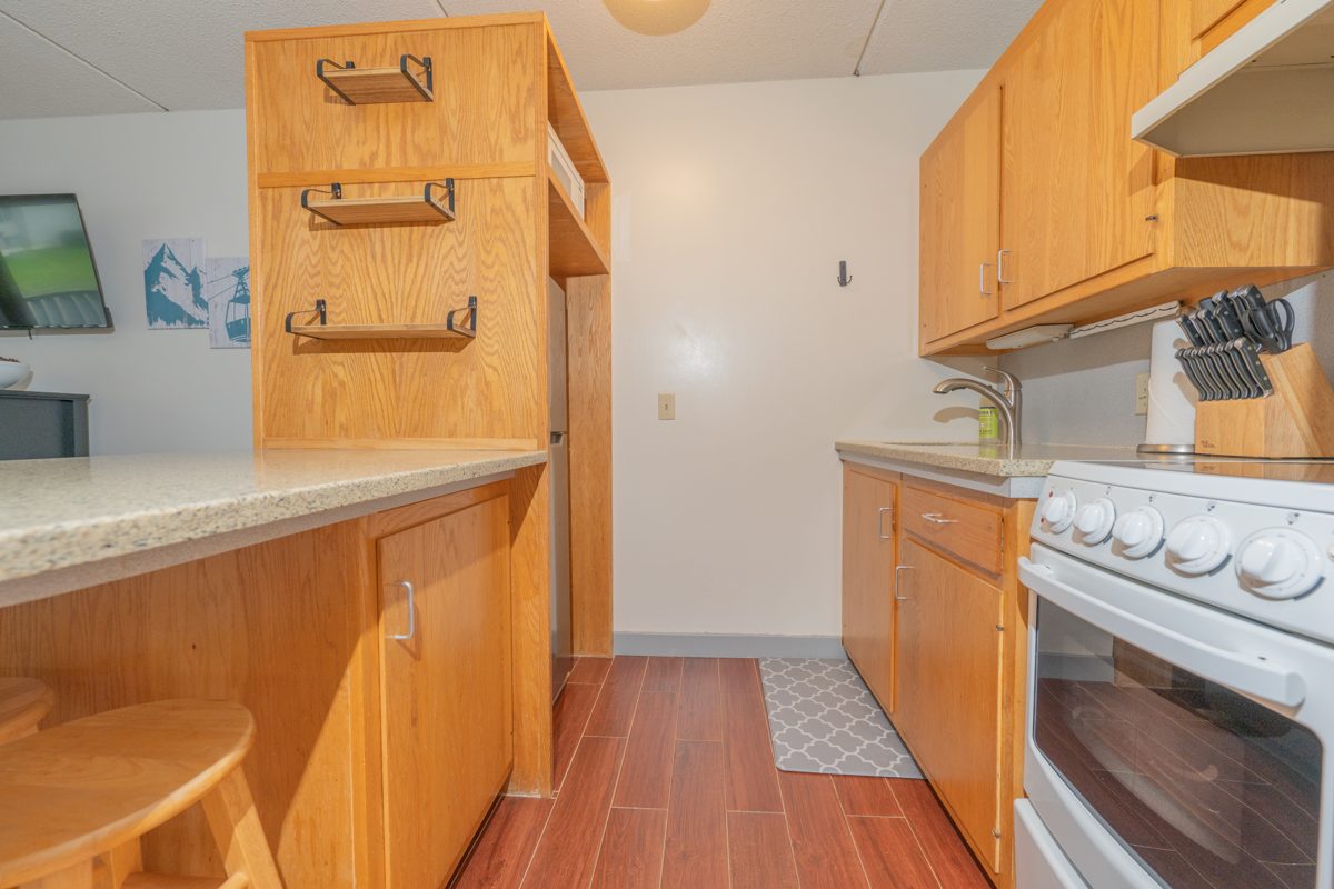 Galley kitchen at Ski Stash Smuggs with stove and oven, sink, knife block and breakfast bar with stools